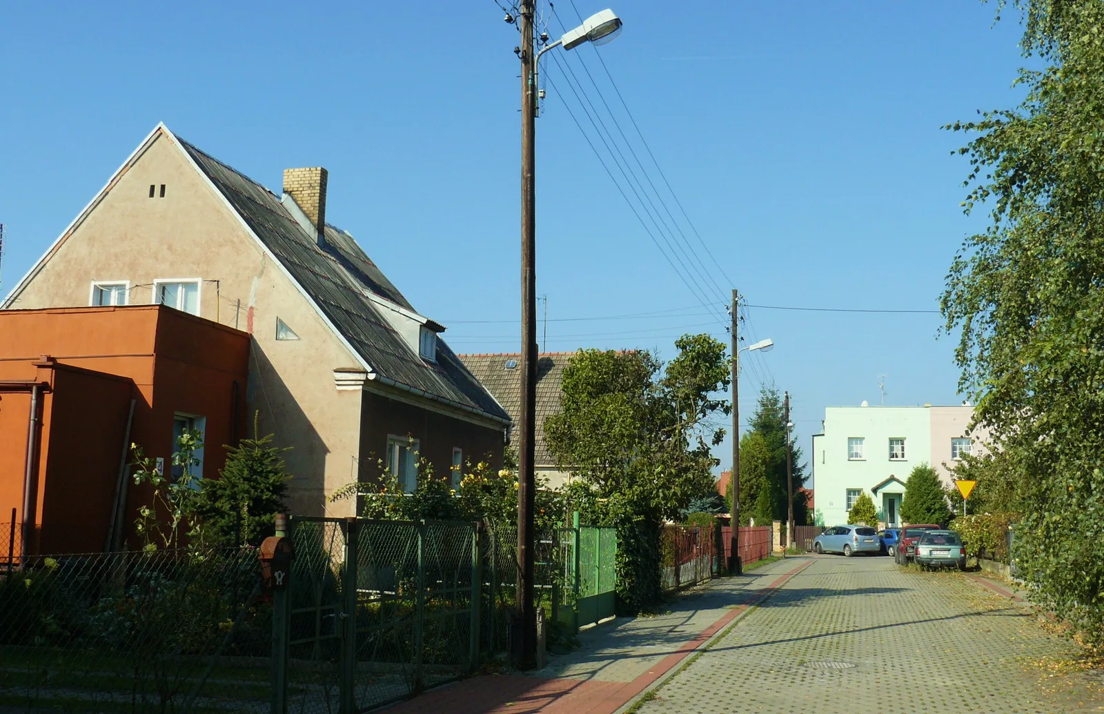 Ulica Węgorzewska na Podolanach w Poznaniu z domami, ogrodzeniami i zielenią